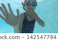 Young girl swimming underwater waving with her hands 142547784