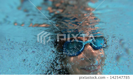 Young girl swimming underwater with air bubbles Young girl swimming underwater with air bubbles 142547785