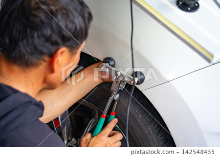 Removing dents on the car. PDR technology. Car body repair without painting. 142548435