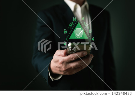 Businessman holding smartphone with secure cyber data protection hologram. Digital internet network security concept for corporate business technology and online privacy safety system. Businessman holding smartphone with secure cyber data protection hologram. Digital internet network security concept for corporate business technology and online privacy safety system. 142548453