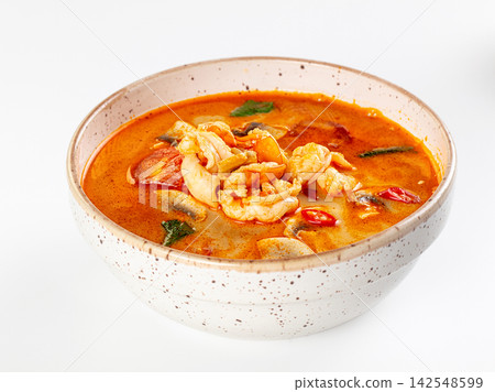 Spicy tom yum soup with prawns in speckled ceramic bowl on white background Spicy tom yum soup with prawns in speckled ceramic bowl on white background 142548599