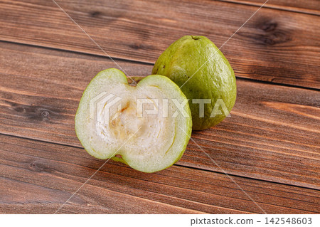 Fresh green guava cut in half on rustic wooden surface Fresh green guava cut in half on rustic wooden surface 142548603
