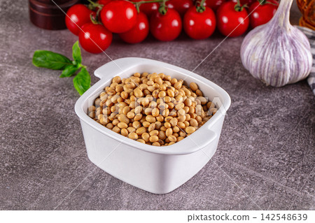 Soybeans in white ceramic bowl with cherry tomatoes and garlic on textured surface Soybeans in white ceramic bowl with cherry tomatoes and garlic on textured surface 142548639