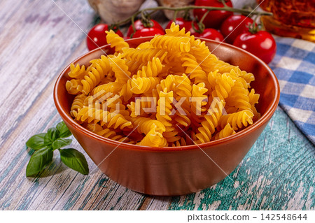 Fusilli pasta in terracotta bowl with cherry tomatoes and basil on rustic wood Fusilli pasta in terracotta bowl with cherry tomatoes and basil on rustic wood 142548644