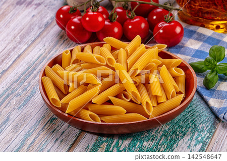 Penne pasta in wooden bowl with cherry tomatoes and basil on rustic table Penne pasta in wooden bowl with cherry tomatoes and basil on rustic table 142548647