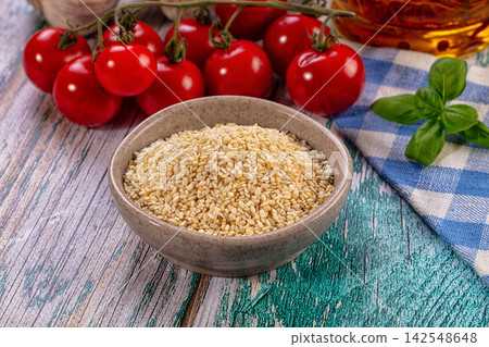 Bowl of sesame seeds with cherry tomatoes and basil on rustic wooden table Bowl of sesame seeds with cherry tomatoes and basil on rustic wooden table 142548648