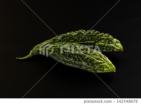 Two green bitter gourds on black background 142548678