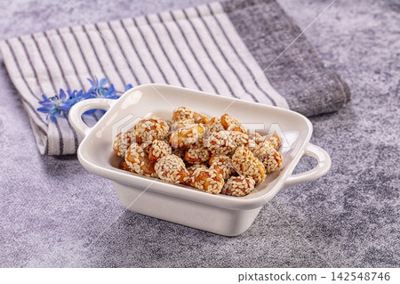 Sesame coated almonds in white ceramic dish on textured gray surface 142548746
