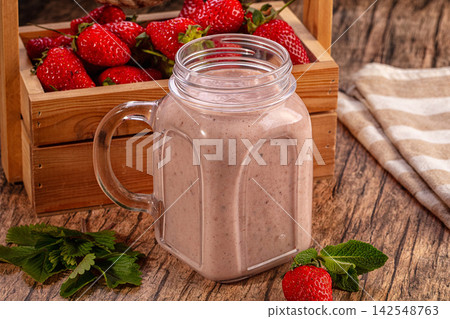 Strawberry milkshake in glass jar with fresh strawberries and mint on rustic wood Strawberry milkshake in glass jar with fresh strawberries and mint on rustic wood 142548763