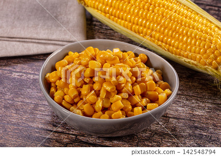 Bowl of cooked corn kernels with whole ear on rustic wooden table Bowl of cooked corn kernels with whole ear on rustic wooden table 142548794
