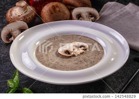 Creamy mushroom soup in white bowl with fresh champignon garnish and basil leaf Creamy mushroom soup in white bowl with fresh champignon garnish and basil leaf 142548829