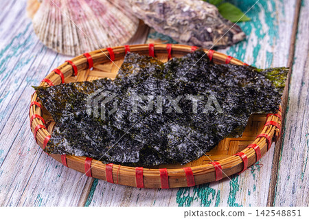 Dark nori seaweed sheets in woven bamboo basket on rustic wooden surface Dark nori seaweed sheets in woven bamboo basket on rustic wooden surface 142548851