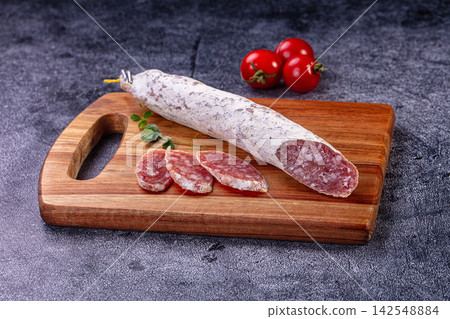 Fuet sausage on wooden cutting board with sliced pieces and cherry tomatoes Fuet sausage on wooden cutting board with sliced pieces and cherry tomatoes 142548884