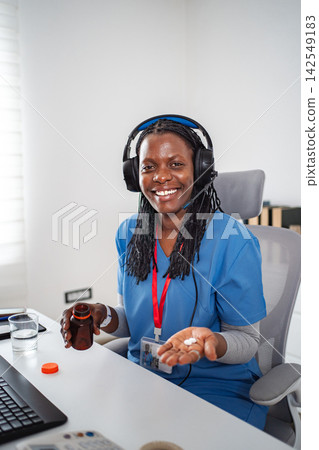Nurse providing telemedicine holding pills during online consultation Nurse providing telemedicine holding pills during online consultation 142549183