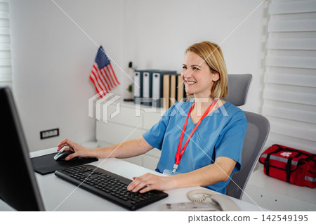 Female healthcare worker smiling while using computer in clinic Female healthcare worker smiling while using computer in clinic 142549195