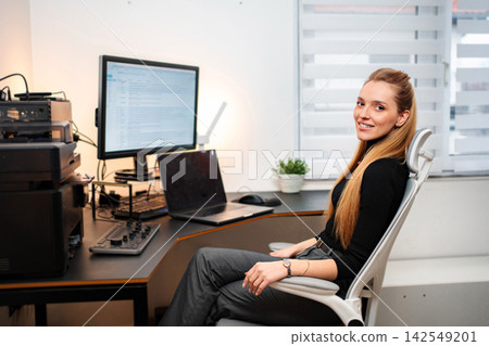 Young adult woman smiling working at computer in office Young adult woman smiling working at computer in office 142549201