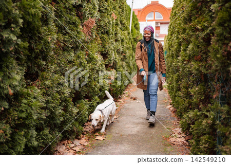 Happy young woman walking dog on street enjoying autumn 142549210
