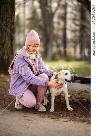 Woman petting happy dog in park during winter walk 142549267