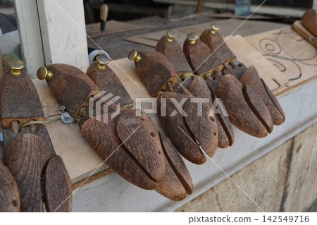 Row of vintage wooden shoe lasts and cobbler forms on bench for shoemaking background and craft workshop display Row of vintage wooden shoe lasts and cobbler forms on bench for shoemaking background and craft workshop display 142549716