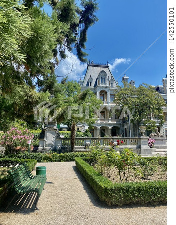 Historic ornate palace stands behind lush formal garden in bright summer sunlight Historic ornate palace stands behind lush formal garden in bright summer sunlight 142550101