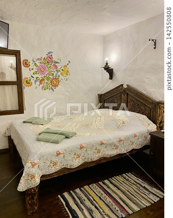 Rustic bedroom with carved wooden bed and colorful traditional floral decor. 142550808