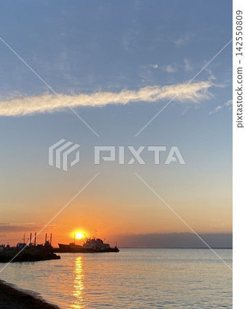 Vessel silhouettes against glowing sunset over calm sea and distant horizon. Vessel silhouettes against glowing sunset over calm sea and distant horizon. 142550809
