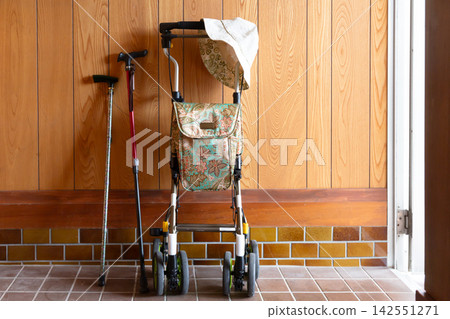 A walker, cane, and hat placed at the entrance; daily life of an elderly person; senior lifestyle. 142551271