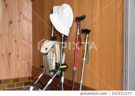 A walker, cane, and hat placed at the entrance; daily life of an elderly person; senior lifestyle. A walker, cane, and hat placed at the entrance; daily life of an elderly person; senior lifestyle. 142551273