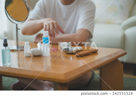 A 40-something man displays skincare products and a facial device on a table in a men's beauty section. A 40-something man displays skincare products and a facial device on a table in a men's beauty section. 142551528