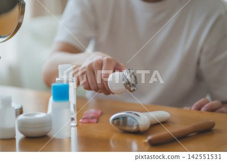 A 40-year-old man picking up a facial beauty device - Men's Beauty A 40-year-old man picking up a facial beauty device - Men's Beauty 142551531