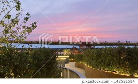 The grand ring roof of the Osaka-Kansai Expo bathed in magic twilight; a view of the sunset from the rooftop of the Italian Pavilion. The grand ring roof of the Osaka-Kansai Expo bathed in magic twilight; a view of the sunset from the rooftop of the Italian Pavilion. 142551594