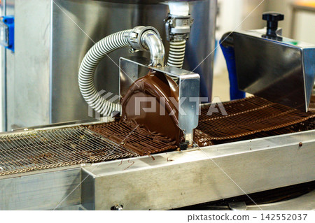 Melted chocolate glazing machine at sweets factory Melted chocolate glazing machine at sweets factory 142552037