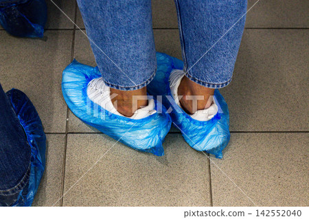 Woman in blue shoe covers for hygiene protection Woman in blue shoe covers for hygiene protection 142552040