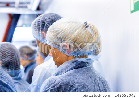Food factory quality control. Food inspector in disposable hairnet and coat for hygiene protection Food factory quality control. Food inspector in disposable hairnet and coat for hygiene protection 142552042