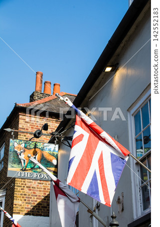 A historic brick building and a Union Jack flag under the bright sunlight in Teddington, a suburb of London. A historic brick building and a Union Jack flag under the bright sunlight in Teddington, a suburb of London. 142552183
