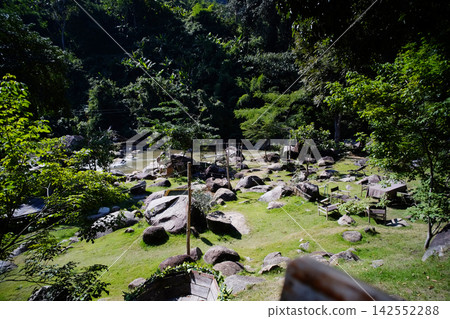 Natural stone area on a grassy slope near a water stream in Thailand 142552288
