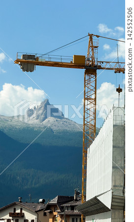 Tower crane on construction site in dolomites mountains Tower crane on construction site in dolomites mountains 142552506