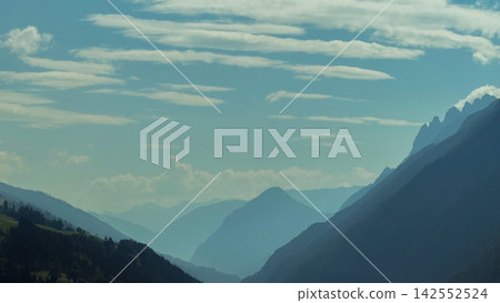 Mountain peaks creating silhouetted layers under blue sky Mountain peaks creating silhouetted layers under blue sky 142552524