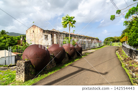 Old derelict military ruins of Meadows Battery and rusty iron naval spheres along an asphalt road in Vigie, Castries, Saint Lucia. Old derelict military ruins of Meadows Battery and rusty iron naval spheres along an asphalt road in Vigie, Castries, Saint Lucia. 142554443