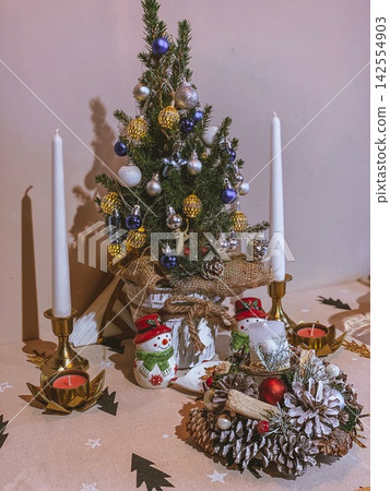 Decorated Christmas tree with candles on table, cozy indoor festive holiday composition Decorated Christmas tree with candles on table, cozy indoor festive holiday composition 142554903
