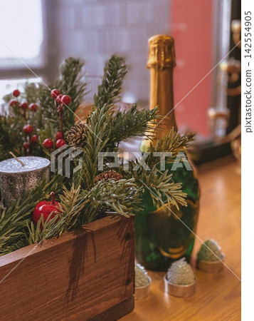 Festive table decor with pine branches and champagne bottle, cozy warm holiday scene Festive table decor with pine branches and champagne bottle, cozy warm holiday scene 142554905