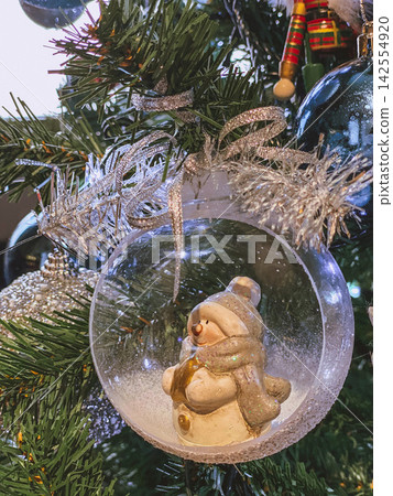Snowman ornament inside glass ball on Christmas tree, sparkling festive cozy close-up Snowman ornament inside glass ball on Christmas tree, sparkling festive cozy close-up 142554920