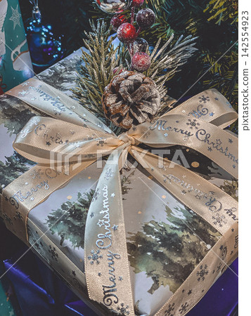 Wrapped Christmas gift with ribbon and pinecone decoration, festive cozy holiday close-up Wrapped Christmas gift with ribbon and pinecone decoration, festive cozy holiday close-up 142554923
