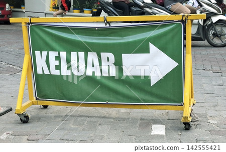 Temporary green exit banner on yellow metal barrier standing on paved ground outdoors. Temporary green exit banner on yellow metal barrier standing on paved ground outdoors. 142555421