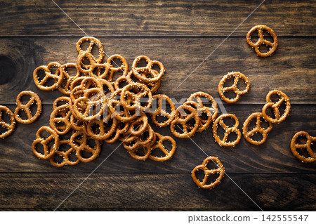 Pretzel mini salted crunchy bretzel snack crackers scattered on dark wooden background table Pretzel mini salted crunchy bretzel snack crackers scattered on dark wooden background table 142555547