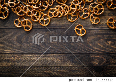 Pretzel mini salted crunchy bretzel snack crackers scattered on dark wooden background table Pretzel mini salted crunchy bretzel snack crackers scattered on dark wooden background table 142555548