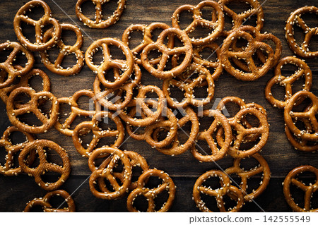 Pretzel mini salted crunchy bretzel snack crackers scattered on dark wooden background table Pretzel mini salted crunchy bretzel snack crackers scattered on dark wooden background table 142555549