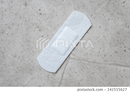 Medical adhesive plaster after vaccination on the stone background. Fabric white bandage like first help for wound on the damage skin. Space for text. Medical adhesive plaster after vaccination on the stone background. Fabric white bandage like first help for wound on the damage skin. Space for text. 142555627
