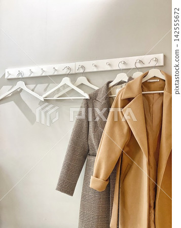 Minimalist wardrobe interior with stylish coats on hangers, neutral tones, modern fashion storage and clothing organization concept Minimalist wardrobe interior with stylish coats on hangers, neutral tones, modern fashion storage and clothing organization concept 142555672