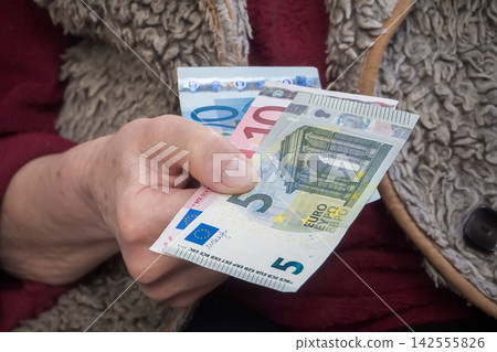 Elderly woman holding euro cash illustrating high winter heating costs and inflation crisis Elderly woman holding euro cash illustrating high winter heating costs and inflation crisis 142555826